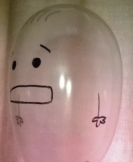 Inflated condom with a face drawn on it