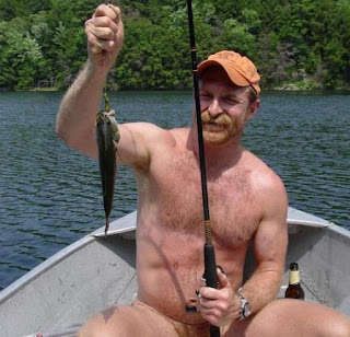Naked man on a boat holding a fish he's just caught.